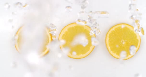 Super Slow Motion Shot of Splashing Water to three orange Slices view from above. — ストック動画