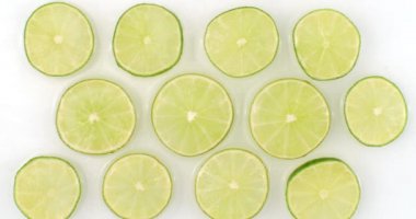 Yavaş çekimde, su, sulu bir narenciye üzerine beyaz arka planda bir sürü limon dökülür. Vejetaryen ve Fructoryalılar