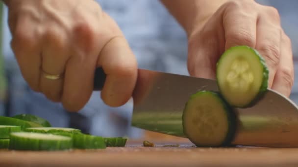 Couper un couteau sur une planche de bois fermer les concombres dans la cuisine. broyer . — Video