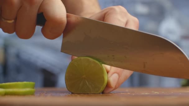 Schneiden Sie mit einem Messer auf einem Holzbrett Nahaufnahme grüne Linde in der Küche. Schreddern. — Stockvideo