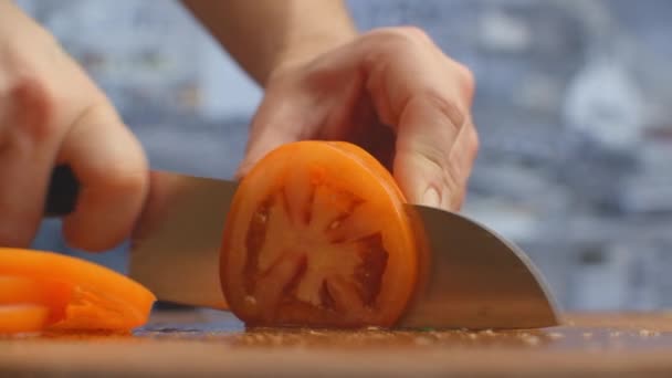 Gros plan d'une femme coupant et coupant la tomate au couteau sur une planche de bois . — Video