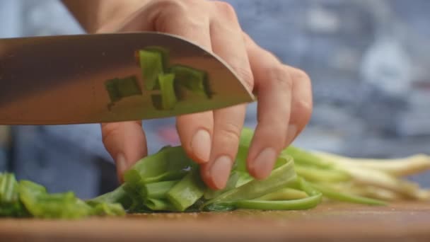 Yeşil soğan kesmek için. Tahtadaki yeşil soğanları kesiyor. Sağlıklı yemek.. — Stok video