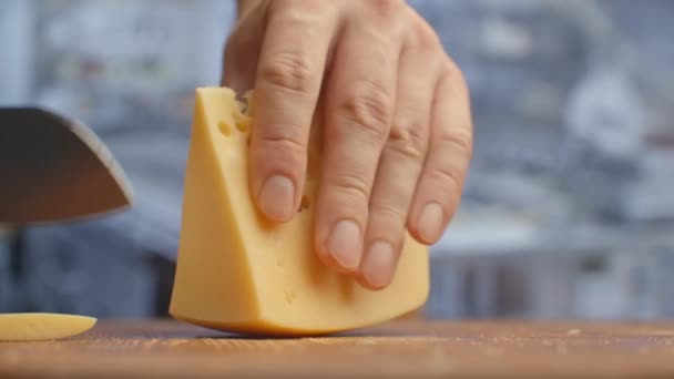 Vágd fel a sárga lyukas sajtot egy fa deszkán. foszlány — Stock videók
