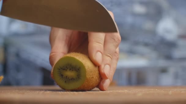 Schneiden Sie mit einem Messer auf einem Holzbrett Nahaufnahme Kiwi in der Küche. Schreddern. — Stockvideo