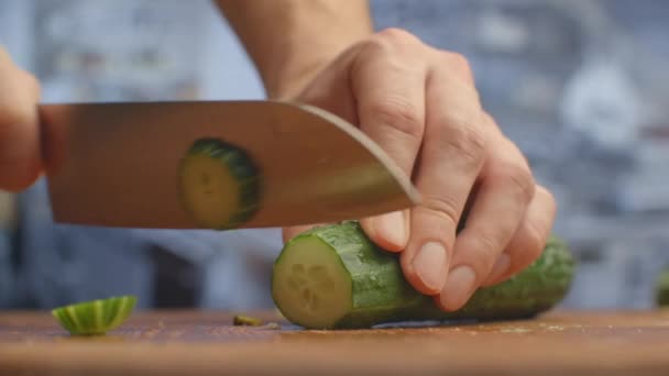 Cortar un cuchillo en una tabla de madera primeros planos pepinos en la cocina. triturar . — Vídeo de stock