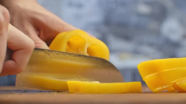 Close-up de pimentas amarelas cortadas em uma placa na cozinha em uma placa de madeira — Vídeo de Stock