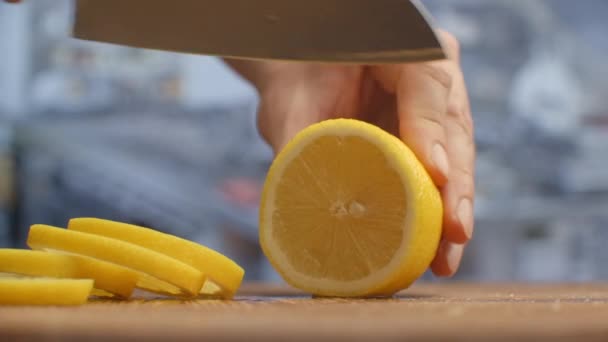 Řezaný nožem na dřevěné desce zblízka s citrónem v kuchyni. skartováno. — Stock video
