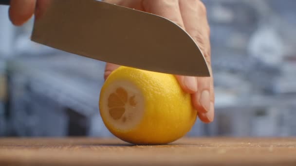 Cortar con un cuchillo en una tabla de madera primer plano de un limón en la cocina. triturar . — Vídeo de stock