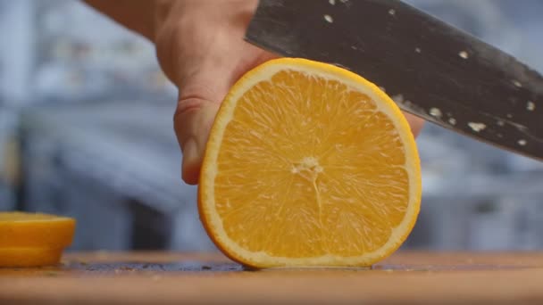 Nahaufnahme einer geschnittenen Orange auf einem Brett in der Küche auf einem Holzbrett. — Stockvideo