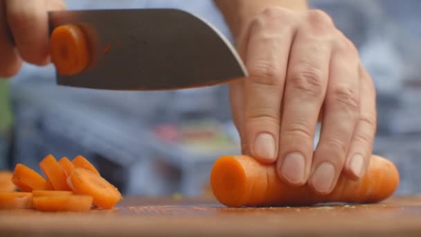 Vrouw snijden wortel op tafel, close-up. — Stockvideo