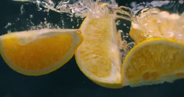 Αρκετά φρούτα λεμονιού πέφτουν μέσα σε μια δεξαμενή νερού και διαταράσσουν το νερό. Τρία φωτεινά κίτρινα φρούτα λεμονιού πέφτουν μέσα σε μια δεξαμενή νερού και επιστρέφουν στην επιφάνεια. — Αρχείο Βίντεο