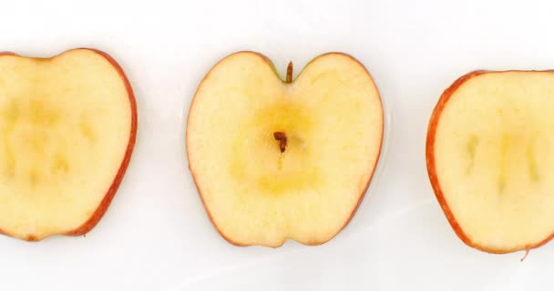 3 apples lie on a white in background in slow motion falling water splashes — 비디오