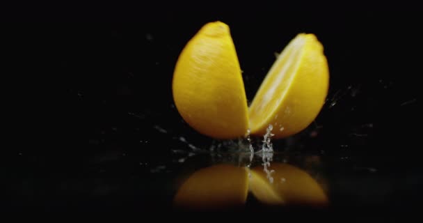 Zeitlupe saftige Zitrone mit Tropfen und zerbricht in 2 Teile mit Spritzern — Stockvideo