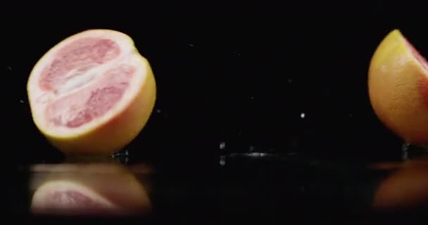 Slow motion. juicy grapefruit with drops and breaks into 2 parts with spray — 비디오