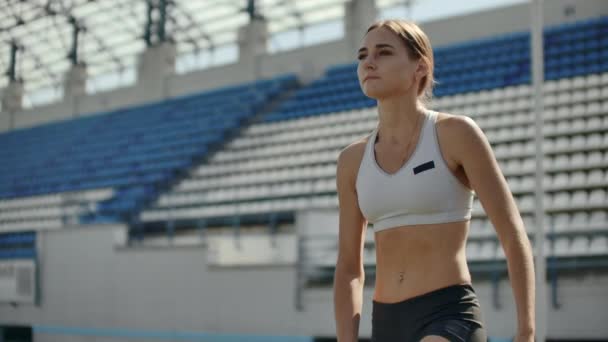 Güzel kadın atlet stadyumda nefes alıyor ve yarışa başlamaya hazırlanıyor. Yarış için motivasyon ve aton. Konsantrasyon ve tutum. — Stok video