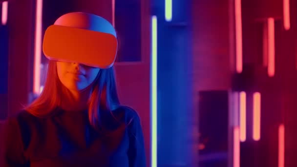 Giovane donna mettendo VR auricolare sullo spettatore in luci al neon — Video Stock