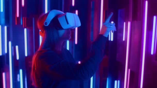 Wanita mengenakan headset VR lereng cepat dari sisi ke sisi saat bermain di ruang gelap diterangi lampu neon . — Stok Video