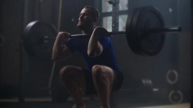 Young sportsman lifting heavy barbell. Healthy, muscular. Strong man doing barbell snatch exercise at the gym in slow motion. Sportsman on exercise mat doing situps in gym. 
