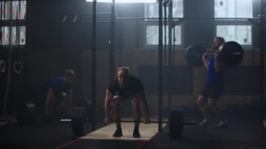 Three fitness man bodybuilder training using barbell weightlifting exercise muscular sportsman power lifting heavy weight doing squats in gym practice enjoying healthy lifestyle.