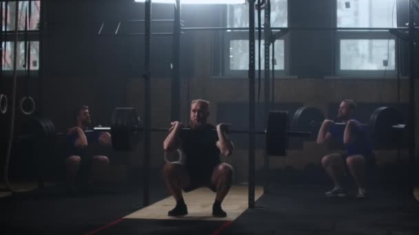 Három fitness férfi testépítő edzés segítségével súlyemelés testmozgás izmos sportoló erő emelés nehéz súly csinál guggolás tornaterem gyakorlat élvezi az egészséges életmód. — Stock videók