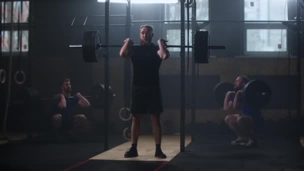 Entrenamiento del culturista del hombre de la aptitud tres usando el ejercicio del levantamiento de pesas de la barra levantamiento de pesas del poder del deportista muscular que levanta peso pesado que hace sentadillas en práctica del gimnasio que disfruta estilo de vida sano . — Vídeos de Stock