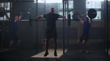 Three fitness man bodybuilder training using barbell weightlifting exercise muscular sportsman power lifting heavy weight doing squats in gym practice enjoying healthy lifestyle.