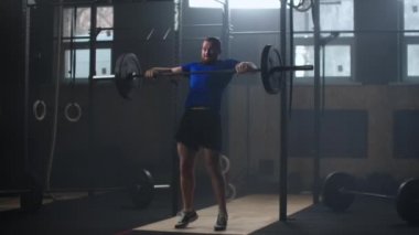 Young sportsman lifting heavy barbell. Healthy, muscular. Strong man doing barbell snatch exercise at the gym in slow motion. Sportsman on exercise mat doing situps in gym. 