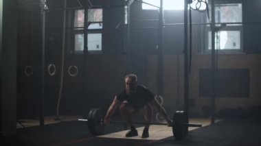 Strong man doing barbell snatch exercise at the gym in slow motion. Male athlete doing barbell snatch exercise in the gym, slow motion.