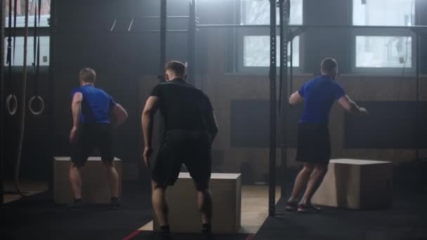 Três fitness man training box jump workout exercício desafio no ginásio desfrutando saudável musculação estilo de vida amigos praticar juntos câmera lenta — Vídeo de Stock