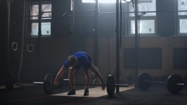 Güçlü adam ağır çekimde spor salonunda halter koparma egzersiz yaparak