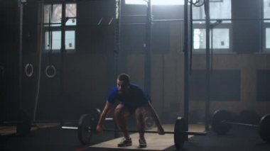 Güçlü adam ağır çekimde spor salonunda halter koparma egzersiz yaparak