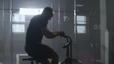 SLow motion: Fitness man on bicycle doing spinning at gym. Fit young female working out on gym bike