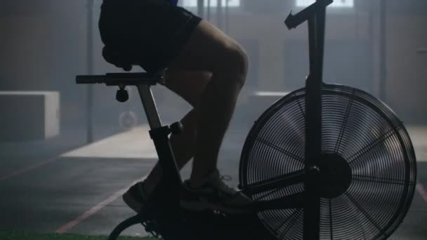 Uomo che fa un intenso allenamento in palestra in bicicletta. Fitness maschile con air bike per allenamento cardio in palestra — Video Stock