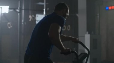 SLow motion: Fitness man on bicycle doing spinning at gym. Fit young female working out on gym bike