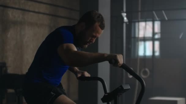 Slow motion: fitnessman op de fiets doet spinning in de sportschool. Past jonge vrouw uit te werken op sportschool fiets — Stockvideo
