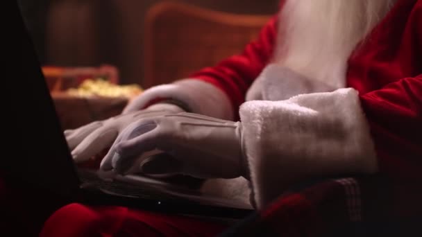Nahaufnahme aus der Hand: Ein älterer Weihnachtsmann mit weißem Bart sitzt auf einem Stuhl und betreibt Internet-Banking. Ihre Konten und E-Mails einsehen. — Stockvideo
