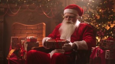 Smiling Santa shifts gifts sitting in a chair