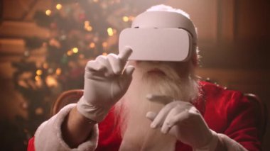 Santa Claus with a white beard and glasses in VR uses hand gestures to control interfaces. Cybernetics Santa Claus