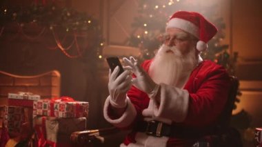 Santa Claus uses a smartphone and writes text messages on the screen