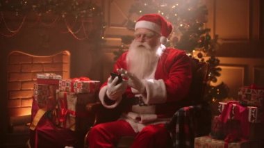 Santa Claus in a magical atmosphere on Christmas eve flips through the social media feed in search of obedient children for gifts