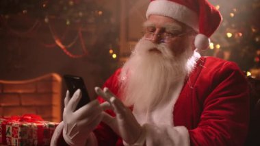 Santa Claus uses a smartphone and chats with his assistants and monitors the situation in the world