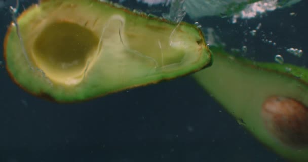 Fatias de abacate maduro Sob a água com bolhas de ar e em câmera lenta. Produto vegetariano saudável fresco e suculento. Ingredientes de salada — Vídeo de Stock