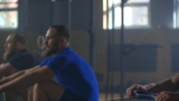 Travaillez sur les muscles du dos. Trois hommes s'entraînent sur une machine à ramer au gymnase. 3 hommes sur la machine d'exercice avec un composé de pondération. Le 3 homme soulève le poids lourd dans la salle de gym. Mouvement lent 