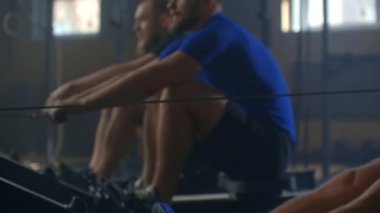 Aktif ve sağlıklı yaşam tarzı, genç atletik mutlu beyaz erkekler kürek çekme makinelerinde birlikte çalışırlar.