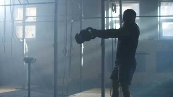 SLO MO Jeune homme balançant la kettlebell dans le centre de fitness 