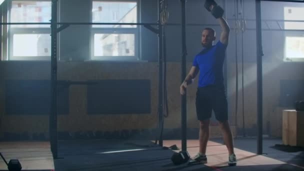 Brutal athlete lifts the Dumbbell above himself, performing a jerk, a spinning push. A man with a beard is engaged in weightlifting on a dark background, portrait. — 비디오