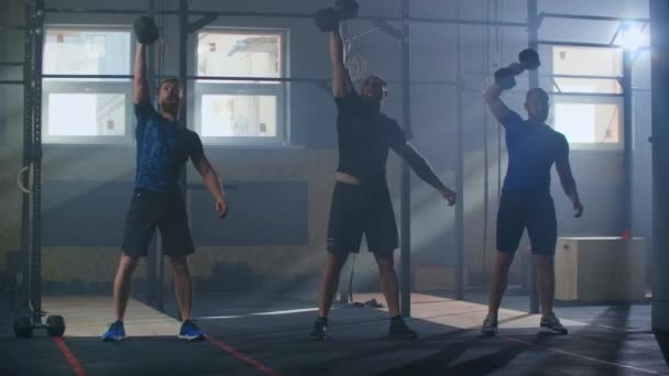 Kruistraining in slow motion. Drie mannelijke vrienden tillen halters omhoog het maken van een dashboard in de sportschool — Stockvideo