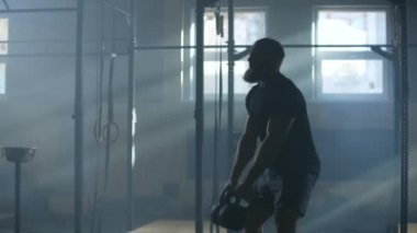 Yavaş hareket eden genç adam fitness merkezinde iki su ısıtıcısını sallıyor.