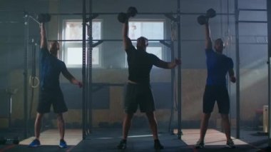 Spor salonunda grup çalışması, erkekler dambılları yavaş çekimde kullanır. Atmosferik fitness odası