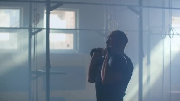 Homme de remise en forme sain faisant de l'exercice en utilisant deux Kettlebell au ralenti 